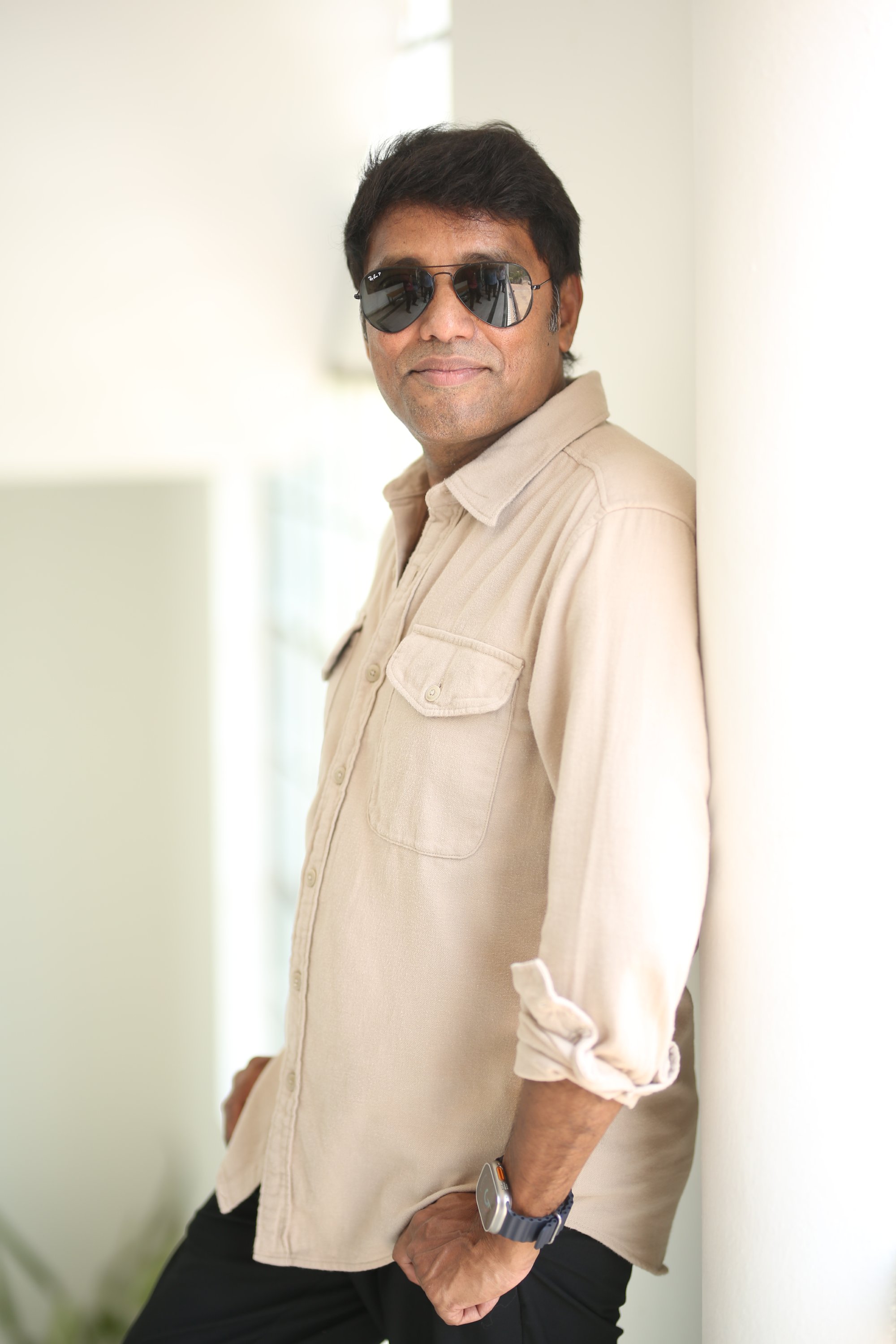 Rathnavelu in stylish casual attire with sunglasses and wristwatch.