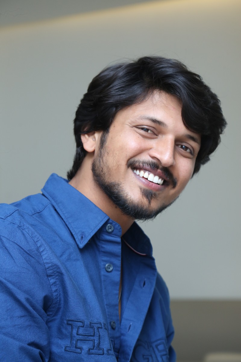 Sumanth Prabhas smiling confidently in a blue button-down shirt