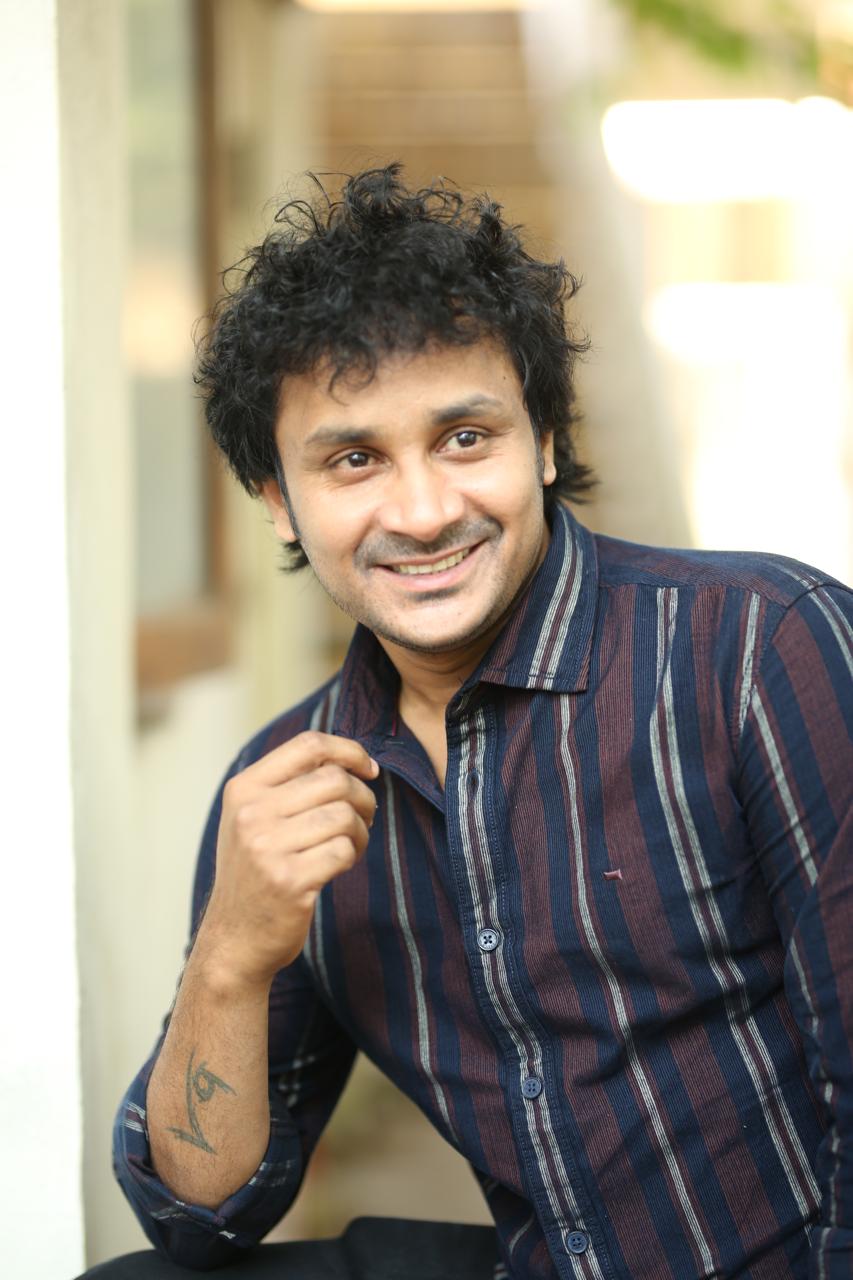 Actor Suvixith Bojja smiling in trendy striped shirt