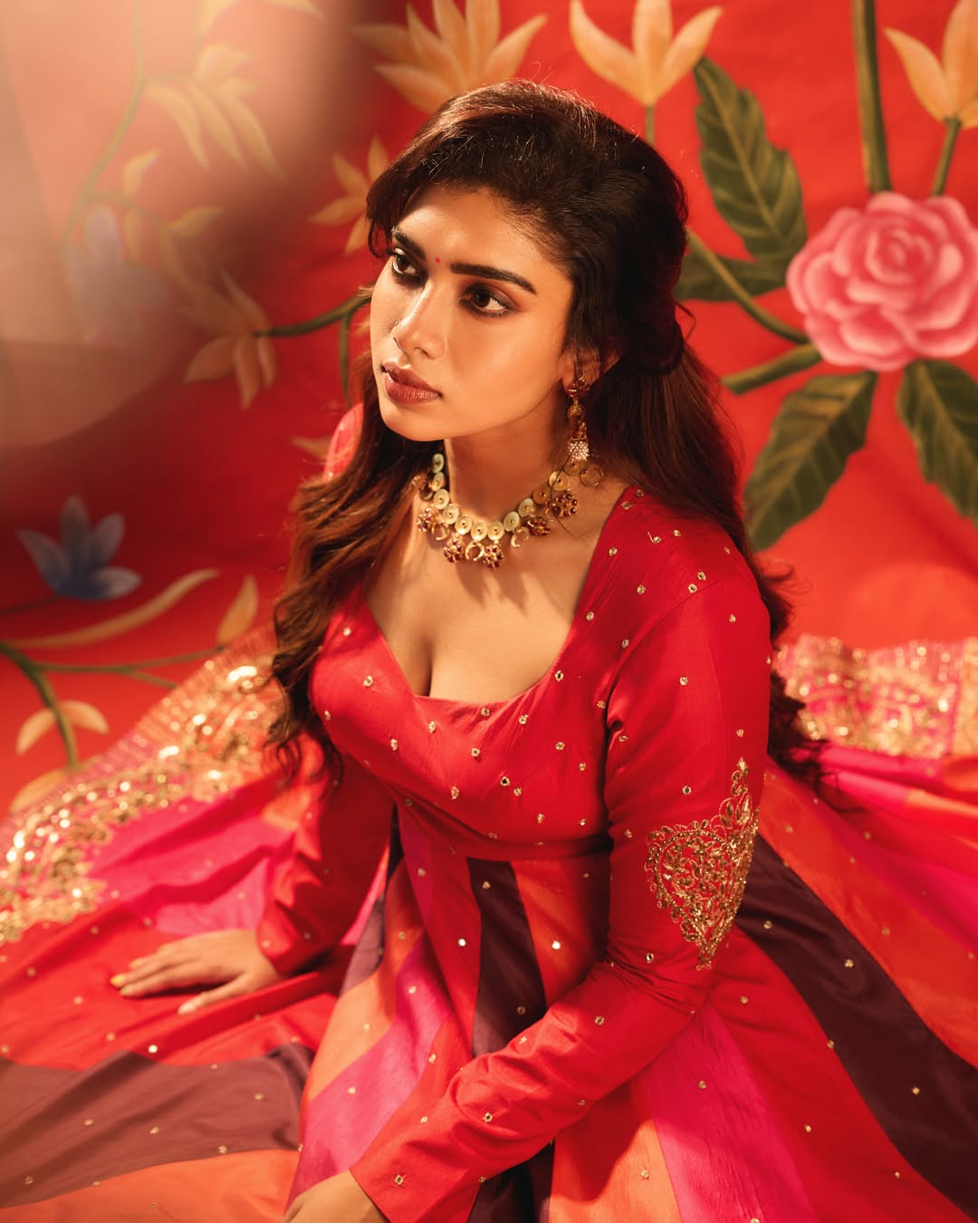 Dushara Vijayan wearing a vibrant red and pink designer ensemble.