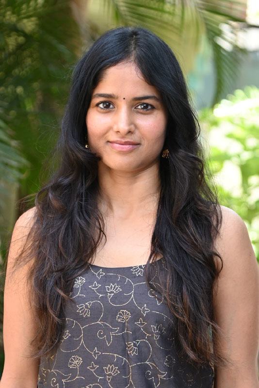 Shalini Kondepudi in a floral-inspired outfit posing against a scenic garden backdrop.